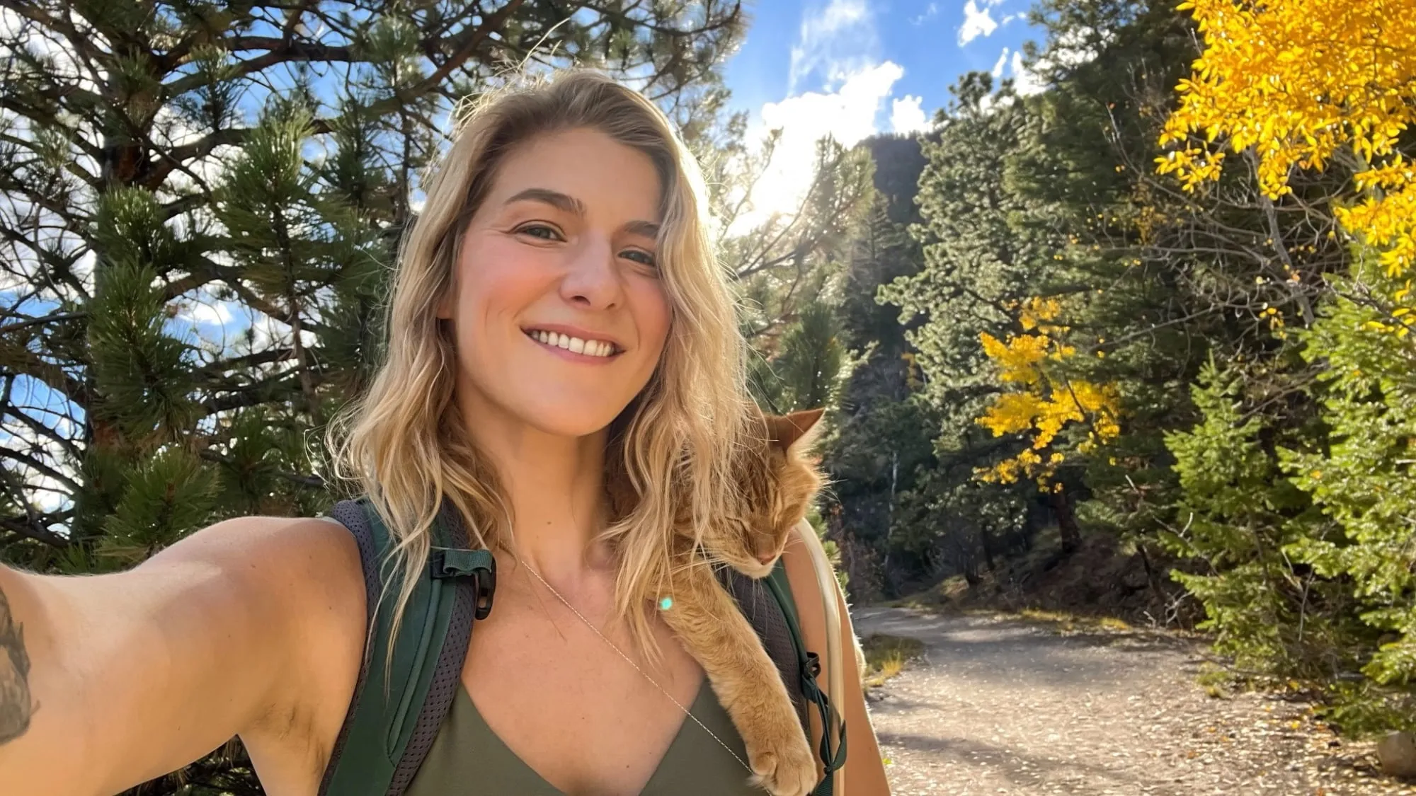 Yvonne smiling on a forest trail with Kya peeking over her shoulder