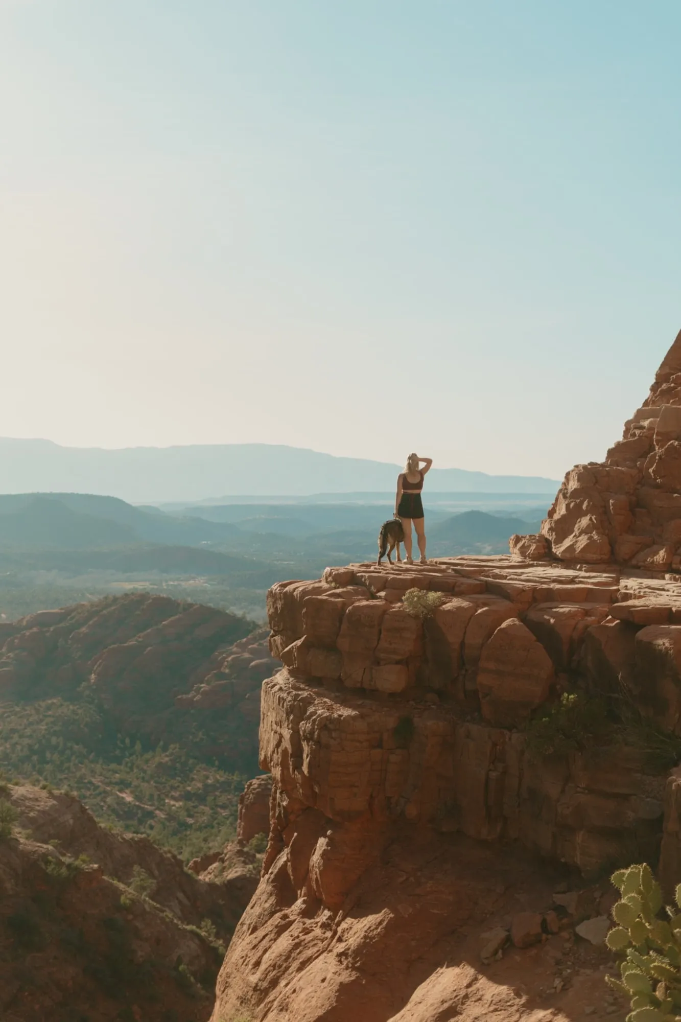 Yvonne and Zahra standing on a red rock cliff overlooking a wide valley